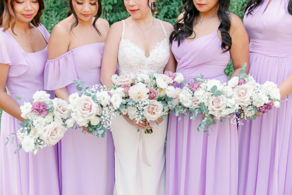 bride with her bridesmaids looking at their pastel and white colored bouquets in Orange County California