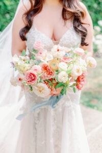 bride holding beautiful soft colored bouquet with a blue ribbon