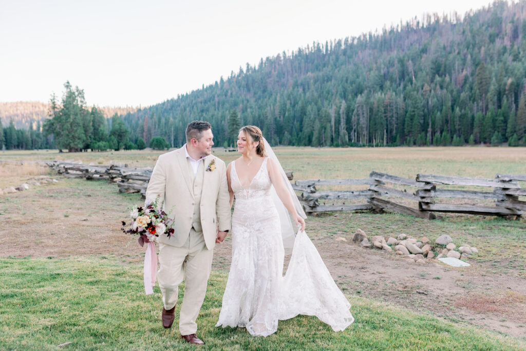 bride and groom walking in a valley with mountains behind them on their wedding day in Lassen California