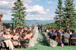 bride and groom holding hands at their wedding ceremony with a view of the mountains behind them at Moonlight Basin in Big Sky Montana
